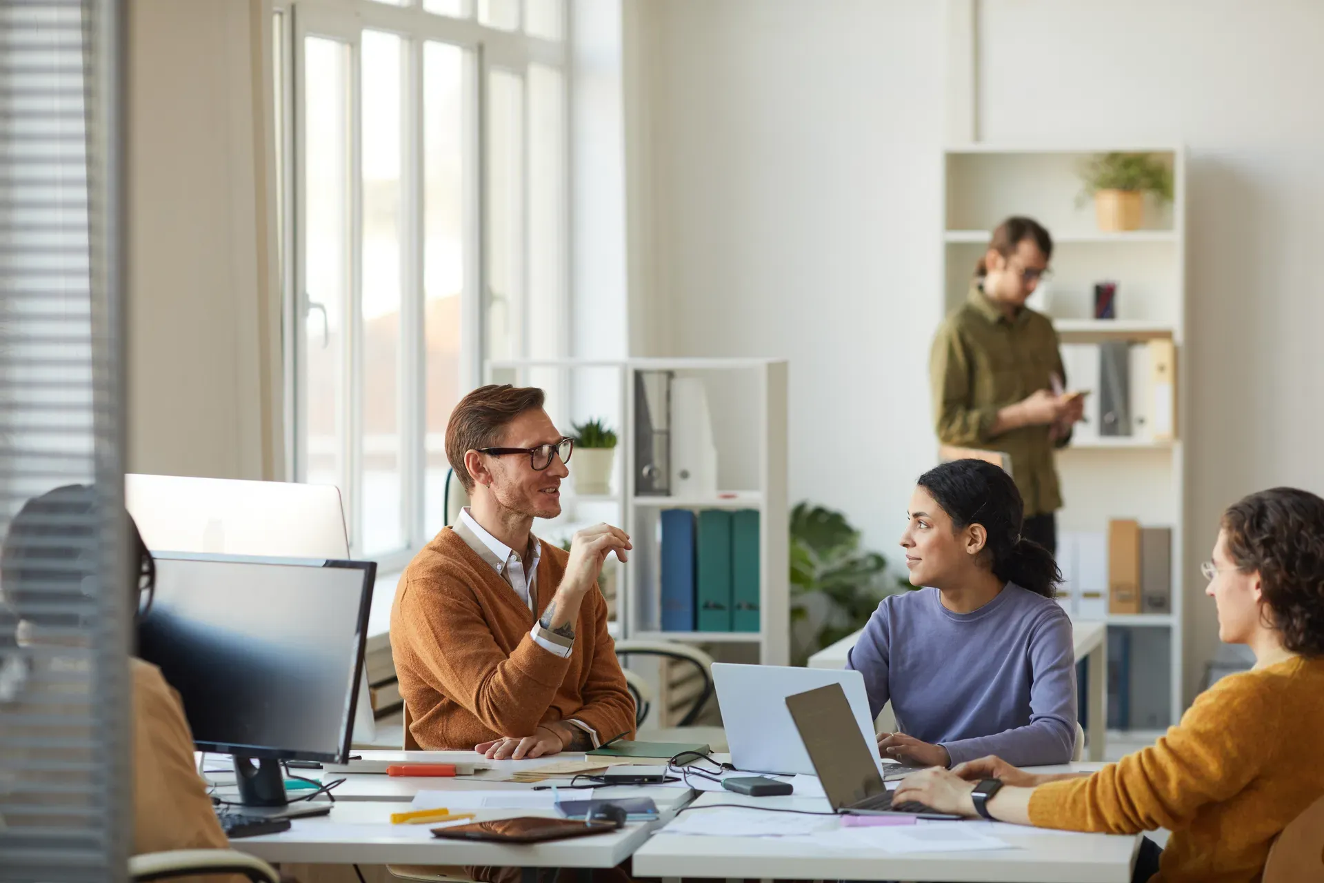 Kleine Runde im Gespräch an Schreibtischen in einem hellen Büro