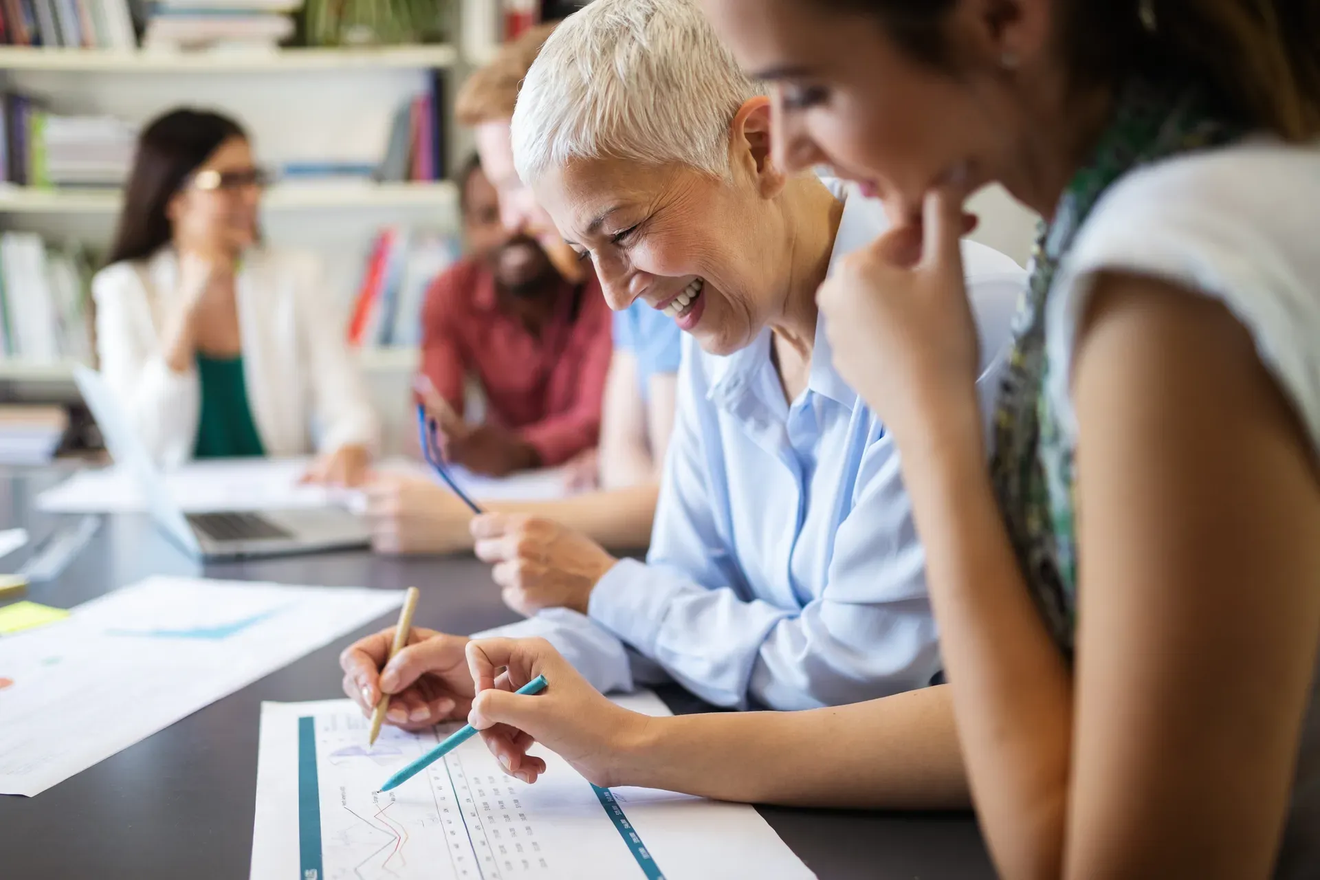 Mehrere Personen arbeiten gemeinsam an Unterlagen auf einem Tisch